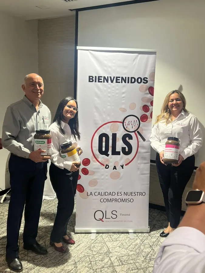 Asistentes con obsequios junto al banner de bienvenida del QLS Day