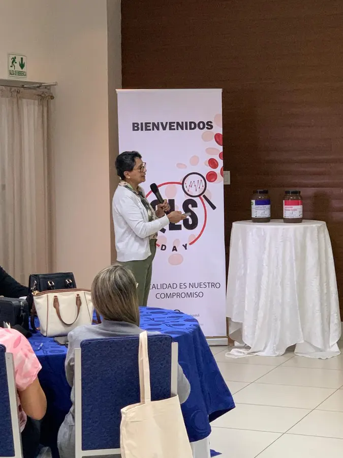 Expositora junto al banner de bienvenida del QLS Day
