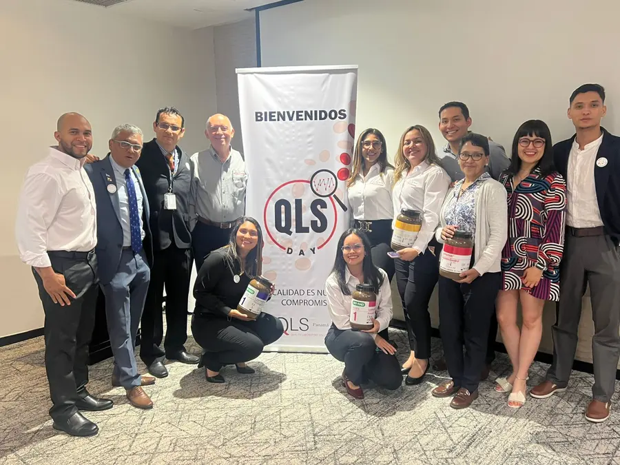 Foto grupal de expositores y asistentes junto al banner del QLS Day