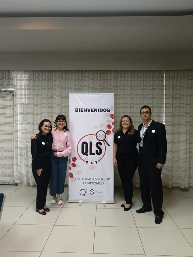 Asistentes junto al banner de bienvenida del QLS Day